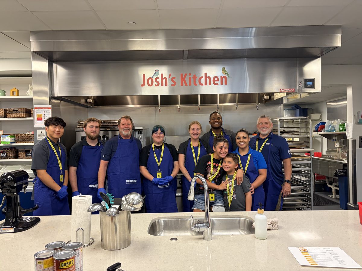 Rust employees in aprons volunteering together in the kitchen at Josh&rsquo;s Kitchen