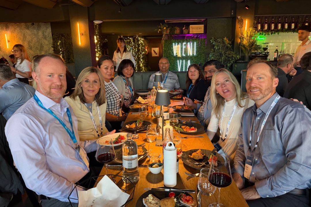 About a dozen people with conference lanyards seated around a long table over dinner in Basel, Switzerland