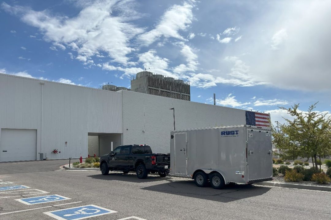 A Rust Automation & Controls branded cargo trailer and pickup truck at the loading area of an industrial facility